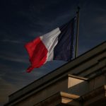 A french flag flies in the sky.