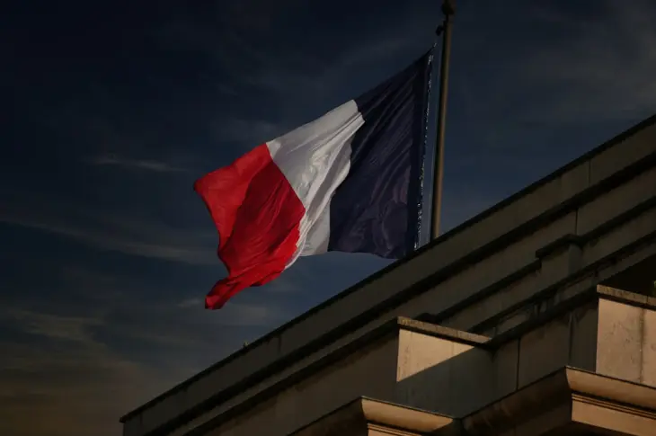 A french flag flies in the sky.