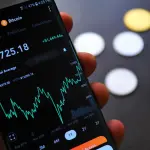 Close-up of Bitcoin trading app on smartphone showing market trends and digital coins.